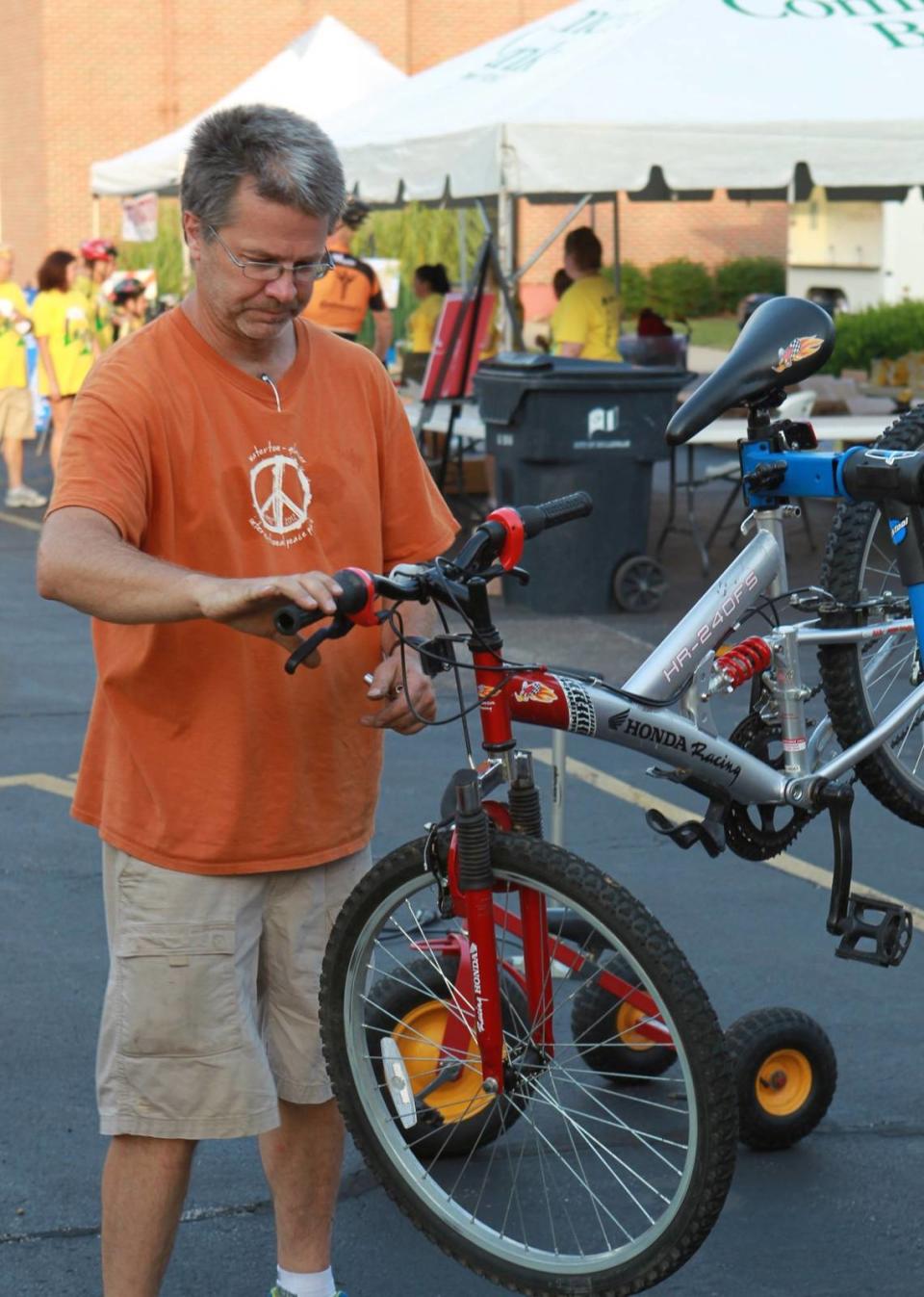 Allan Hogg with Cycle of Giving Books and Bikes repairs a bike before the ride.