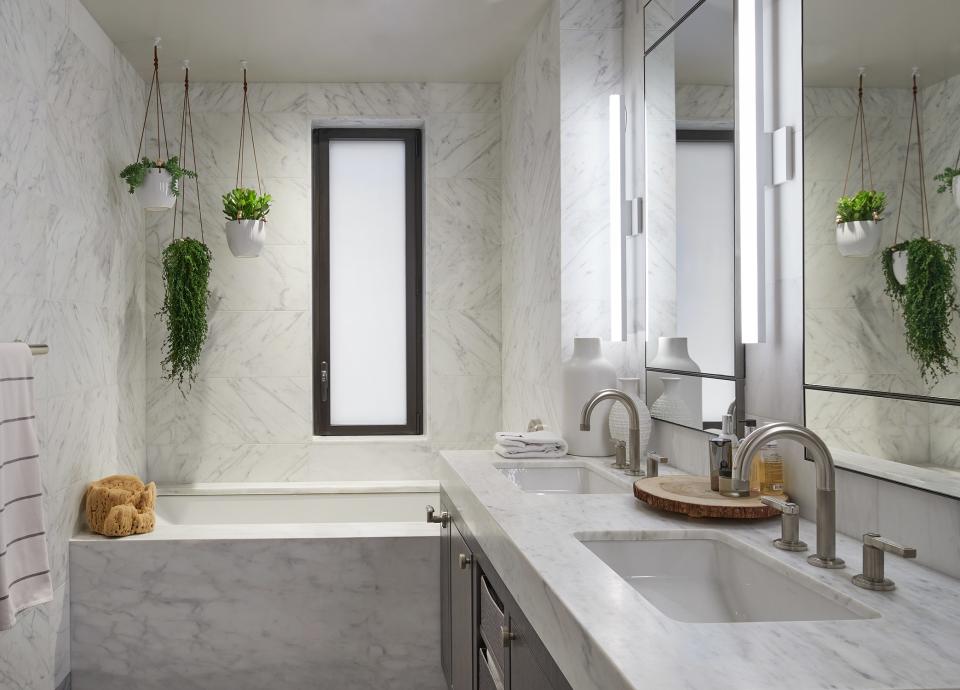 The master bath is clad in Carrera marble, with sink faucets from Kallista. The plant hangers came from just up the street from a supplier in the Flower District.