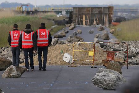 Striking French CGT labour union employees stand near a barricade to block the entrance of the fuel depot of the SFDM company near the oil refinery of Donges, France, May 25, 2016 in protest over proposed new labour laws. REUTERS/Stephane Mahe