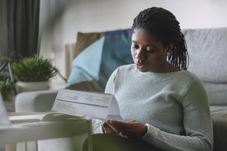 energy  Portrait of a young African American businesswoman reading a utility bill while working remotely from home.