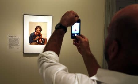 A visitor takes a picture of a photograph of Oscar-winning actor and renowned comedian Robin Williams displayed at the Smithsonian's National Portrait Gallery in Washington August 12, 2014. REUTERS/Larry Downing