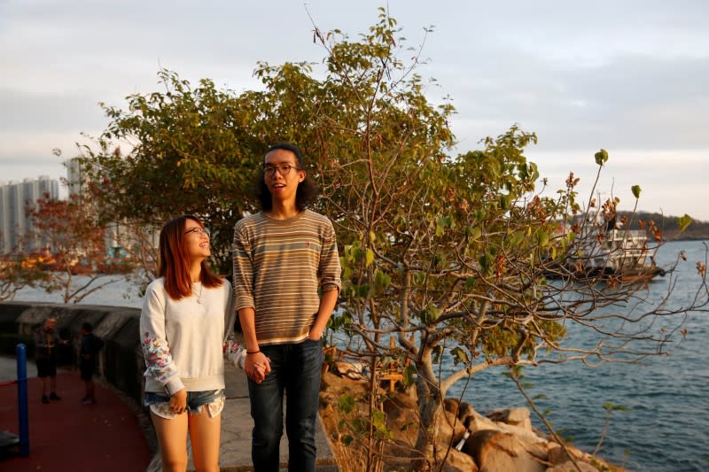 Derek Tai and his girlfriend Ann walk by the sea during sunset in Hong Kong