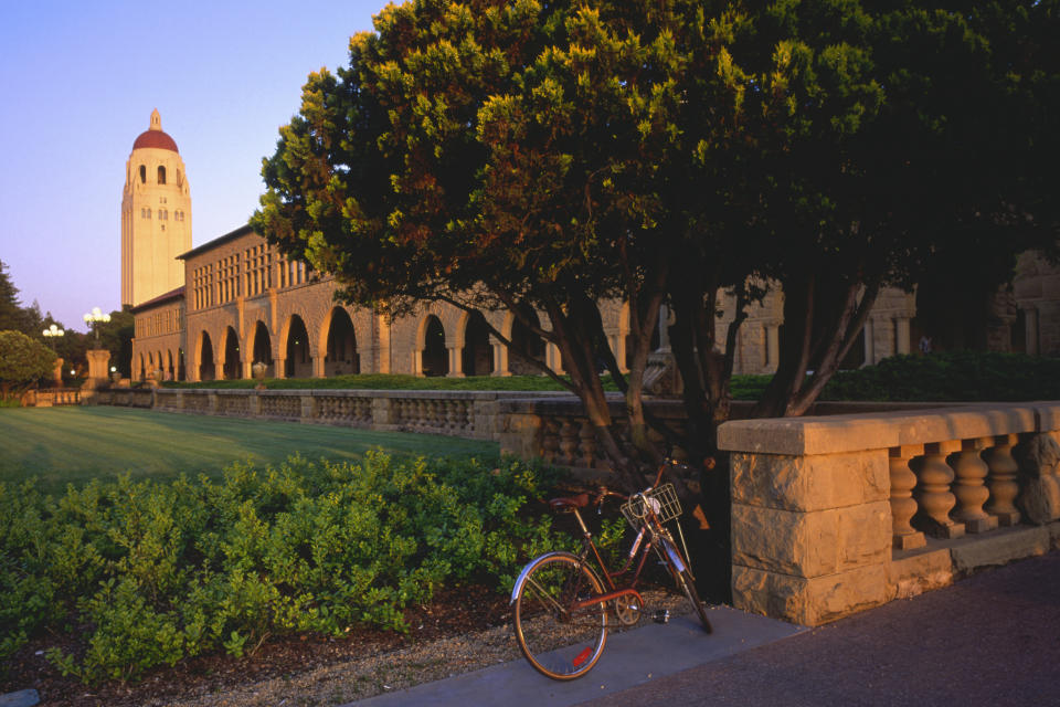 A bicycle stands before a grass lawn looking over to the Hoover Tower.