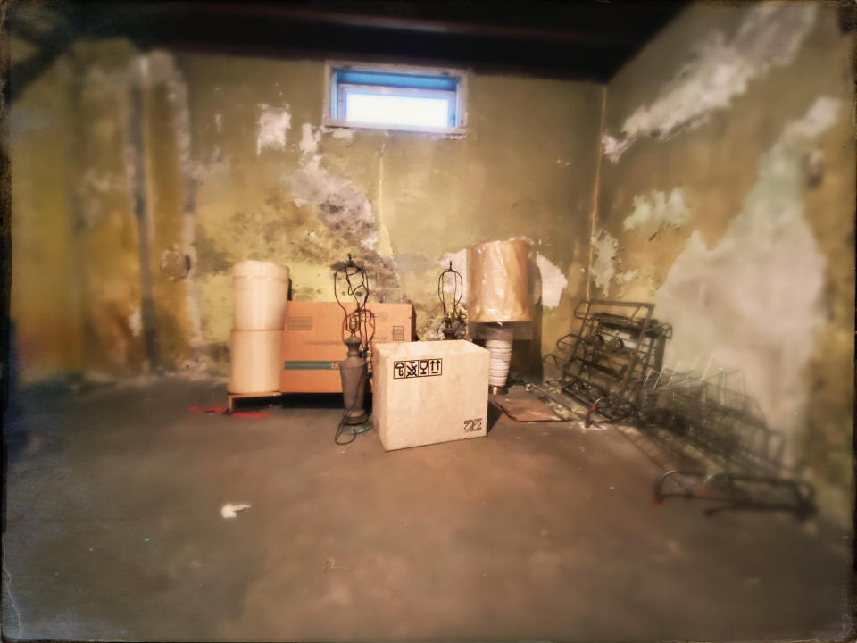 A decrepit-looking room with some old furniture and deteriorating wallpaper