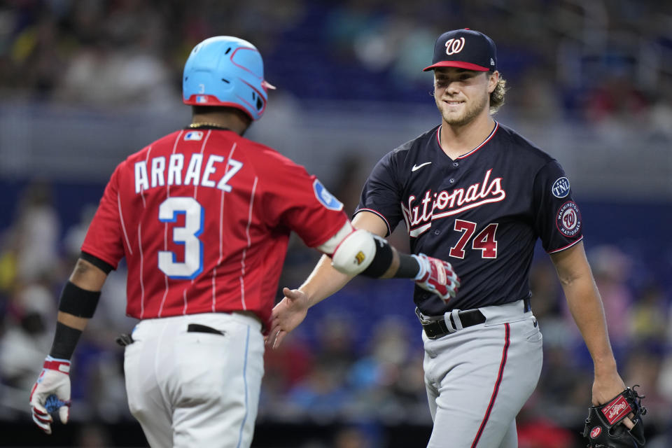 Washington Nationals starting pitcher Jake Irvin (74) and Miami Marlins second baseman Luis Arraez (3) greet each other after Arraez flied out to end the first inning of a baseball game, Saturday, Aug. 26, 2023, in Miami. (AP Photo/Wilfredo Lee)