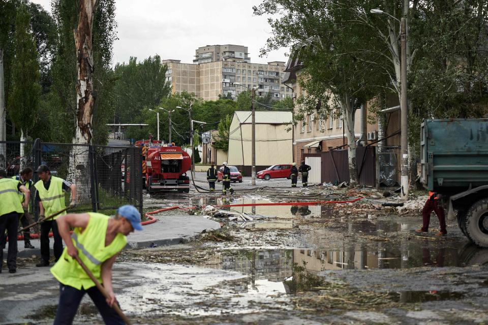 Workers clear debris as firefighters intervene at a medical facility, the site of a missile strike, in the city of Dnipro on May 26 amid the Russian invasion of Ukraine.