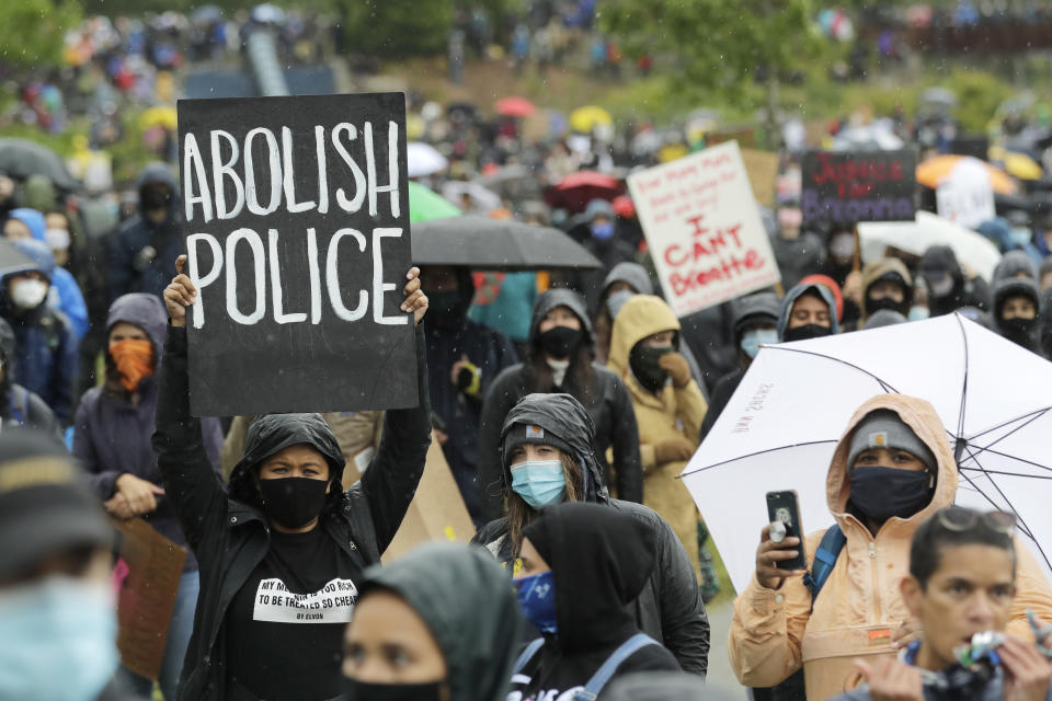 A protester holds a sign that reads "Abolish Police" during a "Silent March" against racial inequality and police brutality that was organized by Black Lives Matter Seattle-King County, Friday, June 12, 2020, in Seattle. Hundreds of people marched for nearly two miles to support Black lives, oppose racism and to call for police reforms among other issues. (AP Photo/Ted S. Warren)