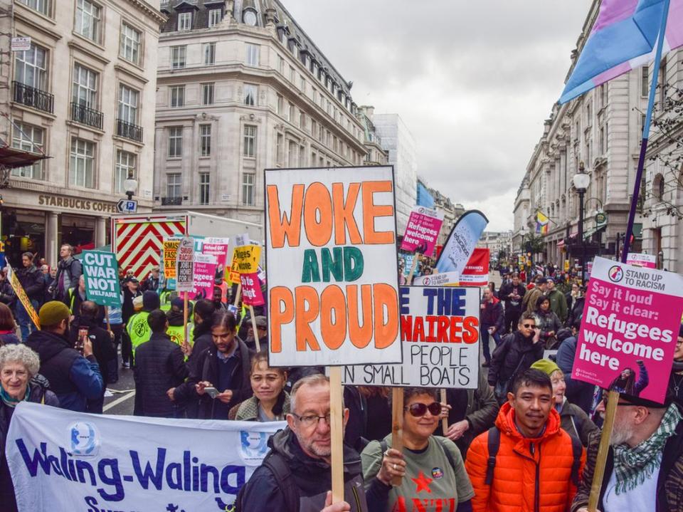 A protester holds a 'Woke and proud' placard during the