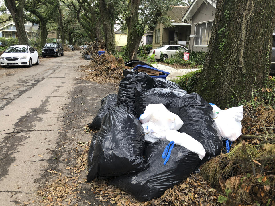 Bags and containers of household garbage and piles of storm debris line a New Orleans street, Friday, Sept. 17, 2021. Nearly three weeks after Hurricane Ida struck the city, many residents are growing angry at the lack of garbage pickups in New Orleans— a problem officials say stems from labor shortages that began with the COVID-19 pandemic and were made worse by the storm. (AP Photo/Kevin McGill)