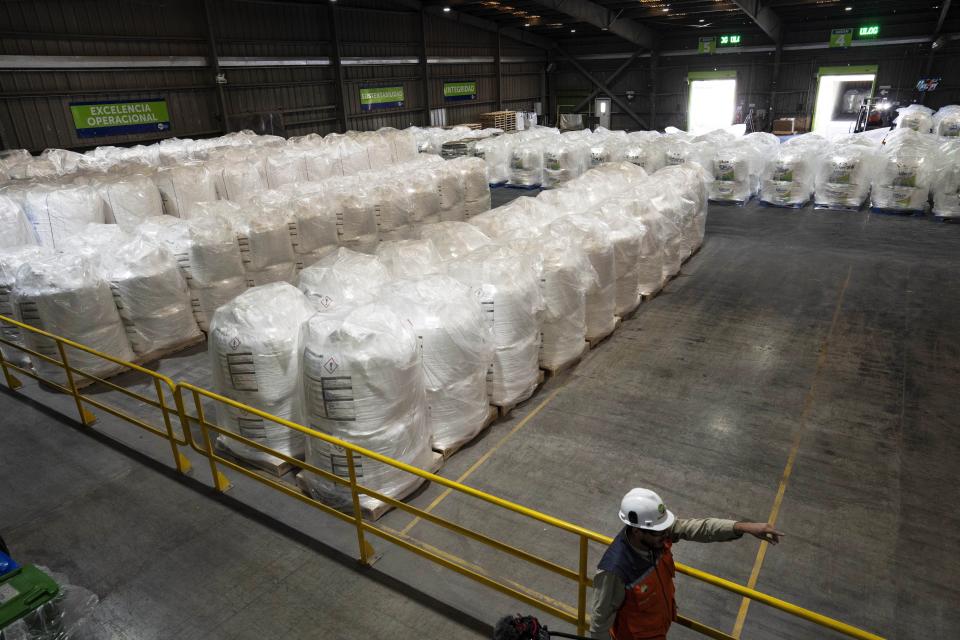 A worker walks next to bags of lithium ready for export at the SQM processing plant in Antofagasta, Chile, Wednesday, April 19, 2023. (AP Photo/Rodrigo Abd)