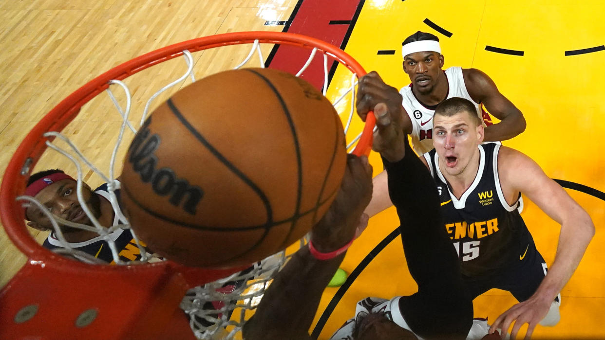  Nuggets and Heat players watch as the ball goes in the basket 