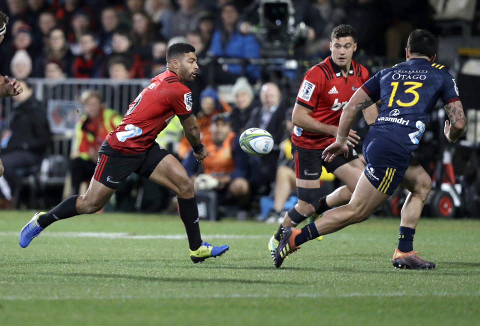 Crusaders Richie Mo'unga, left, passes the ball to teammate David Havili as Highlanders Rob Thompson, right, chases during the Super Rugby quarterfinal between the Crusaders and the Highlanders in Christchurch, New Zealand, Friday, June 21, 2019. (AP Photo/Mark Baker)