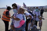 Afghan refugees wearing face masks to prevent the spread of the coronavirus, board an airplane bound for Portugal at the Eleftherios Venizelos International Airport in Athens, on Tuesday, Sept. 28, 2021. The 41 refugees from Afghanistan were relocated as part of a migrant reunification plan agreed between the two countries. (AP Photo/Thanassis Stavrakis)