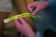 Una enfermera coloca una pulsera con la palabra "vacunado" a un niño tras recibir una dosis de la vacuna de Pfizer-BioNTech contra el COVID-19, en el primer día de la campaña para niños de 5 a 11 años, en el hospital Pereira Rossell, en Montevideo, Uruguay, el 12 de enero de 2022. (AP Foto/Matilde Campodonico)