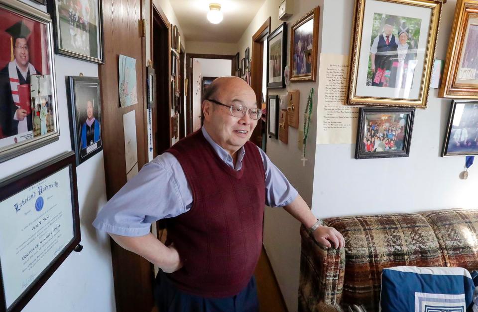 Vue Yang, of Sheboygan, stands in a wall filled with the accomplishments of his family, Wednesday, February 8, 2023, in Sheboygan, Wis.