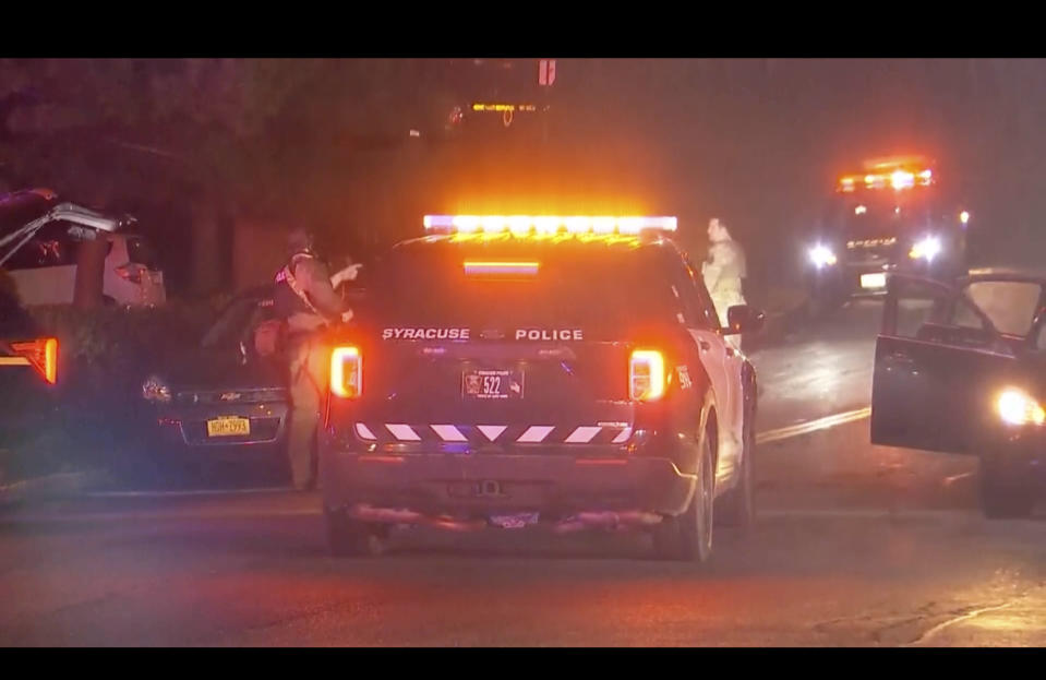 Armed law enforcement officers patrol around the scene of a shooting in Liverpool, N.Y., Sunday, April 14, 2024. A police officer and a sheriff's deputy in upstate New York were shot and killed Sunday night in an exchange of gunfire with a suspect, who also was killed, police said. (WSYR-TV Syracuse via AP)