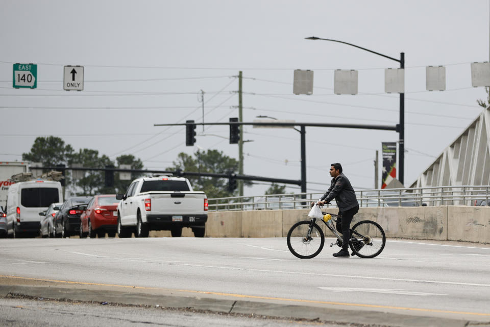 A bicyclist crosses Jimmy Carter Blvd on Tuesday, May 23, 2023, in Norcross, Ga. (AP Photo/Alex Slitz)