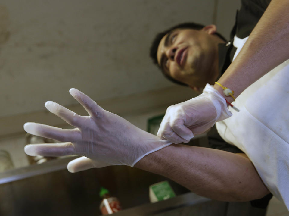 Luis Escamilla puts on gloves before cutting prosciutto at the Hock Farm Restaurant in Sacramento, Calif. at the Hock Farm restaurant in Sacramento, Calif. Under a bill signed last year by Gov. Jerry Brown, chefs and bartenders in California must keep bare hands off food going straight to the plate or the drink glass, and must use gloves or kitchen utensils such as tongs. California, where the law took effect Jan. 1 and will begin enforcement starting in July, will join 41 other states banning bare-hand contact with ready-to-eat food. In February,after receiving a petition from bartenders calling for an exemption for the "disposable glove law" the law's author, Assemblyman Richard Pan, D-Sacramento, a pediatrician, has introduced a bill to repeal the new regulation and revisit the entire issue.(AP Photo/Rich Pedroncelli)