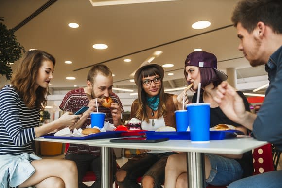 Five young adults eating fast food.