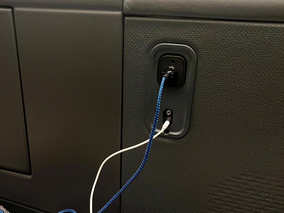 Charging chords plugged into "The Room" business class seat.