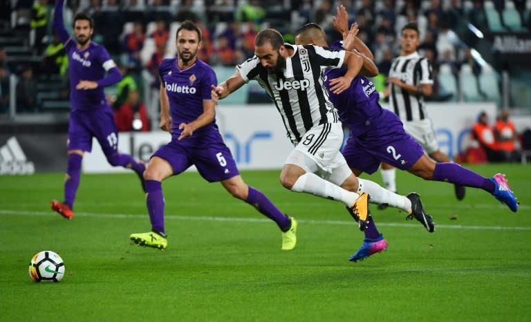 Juventus's forward Gonzalo Higuain (C) fights for the ball with Fiorentina's defender Vice Laurini (R) during the Italian Serie A football match September 20, 2017