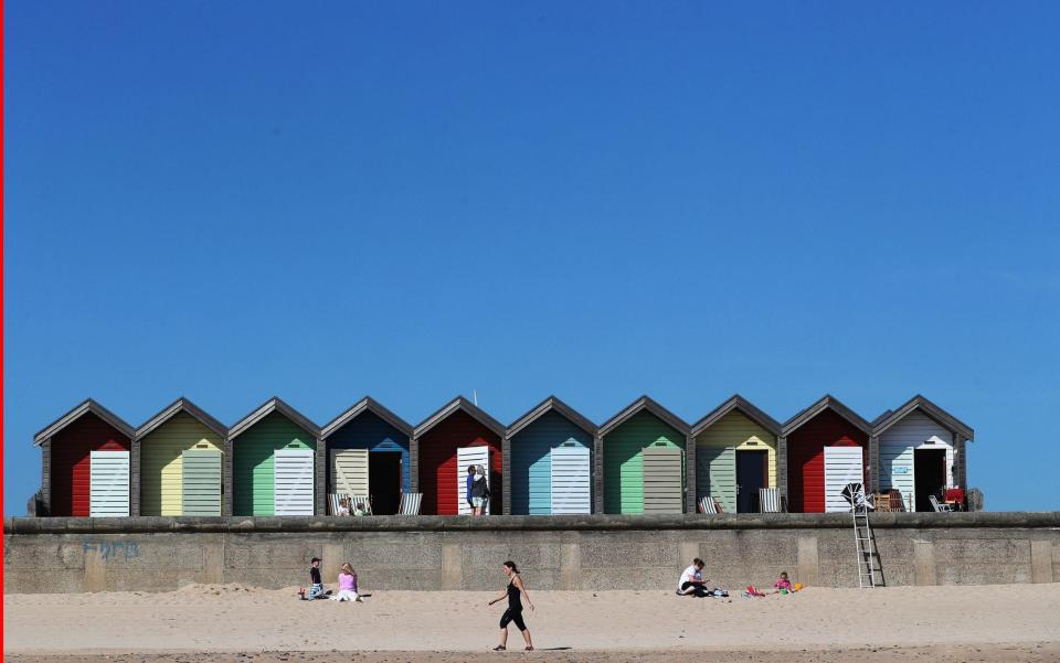  People enjoy the sunshine by the beach huts on Blyth Beach in Northumberland - Credit: PA