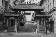 Framed by the Dragon's Gate, a woman crosses Chinatown's Grant Avenue in San Francisco on April 17, 2020. Normally, the months leading into summer bring bustling crowds to the city's famous landmarks, but this year, because of the coronavirus threat they sit empty and quiet. Some parts are like eerie ghost towns or stark scenes from a science fiction movie. (AP Photo/Eric Risberg)