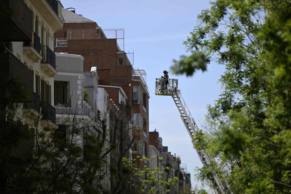 A firefighter inspects a building from a ladder (AFP via Getty Images)