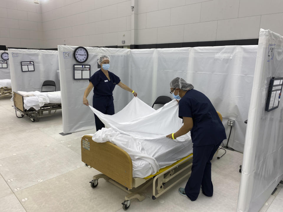 This photo from the California Office of Emergency Services (OES) shows hospital beds set up in the practice facility at Sleep Train Arena in Sacramento, Calif., that is ready to receive patients as needed on Wednesday, Dec. 9, 2020. The practice facility currently has 66 beds. The total bed count between the practice facility and arena, which could be made available for patients at a later date, is over 240. A health official in California's third largest county is urging hospitals to cancel elective surgeries and implement plans for an onslaught of COVID-19 patients, as intensive care units fill up statewide amid spiking virus cases. Dr. Carl Schultz says ambulances have been waiting for hours to unload patients because Orange County emergency rooms are so backed up. He urged hospitals to begin expanding capacity immediately. California's hospitalizations already are at record levels, leaving less than 1,500 of the 7,800 total ICU beds available. (California OES via AP, File)