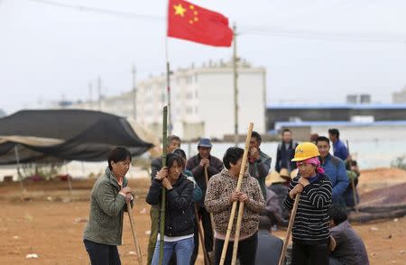 Villagers guard the entrance to Fuyou village next to the Chinese national flag in Jinning county, Kunming, Yunnan province October 15, 2014. REUTERS/Wong Campion