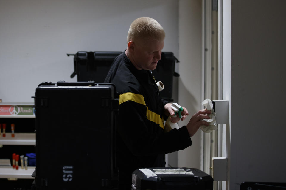 U.S. Army Field Band member Sgt. 1st Class Daniel Goff, originally from Morgantown, W.Va., sanitizes a light switch during rehearsal of their daily "We Stand Ready" virtual concert series at Fort George G. Meade in Fort Meade, Md., Wednesday, March 25, 2020. The Army Field Band's mission is to bring the military's story to the American people. And they're not letting the coronavirus get in the way. (AP Photo/Carolyn Kaster)