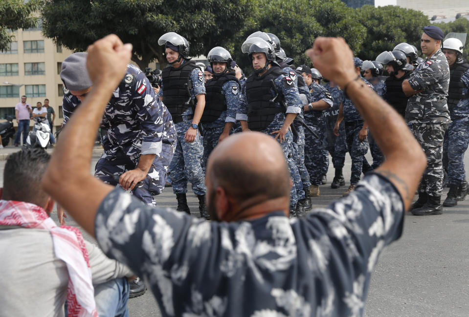 Anti-government protesters blocking a main highway, raises up his hands after riot police prepare to remove them and open the road in Beirut, Lebanon, Saturday, Oct. 26, 2019. The removal of the roadblocks on Saturday comes on the tenth day of protests in which protesters have called for civil disobedience until the government steps down. (AP Photo/Hussein Malla)