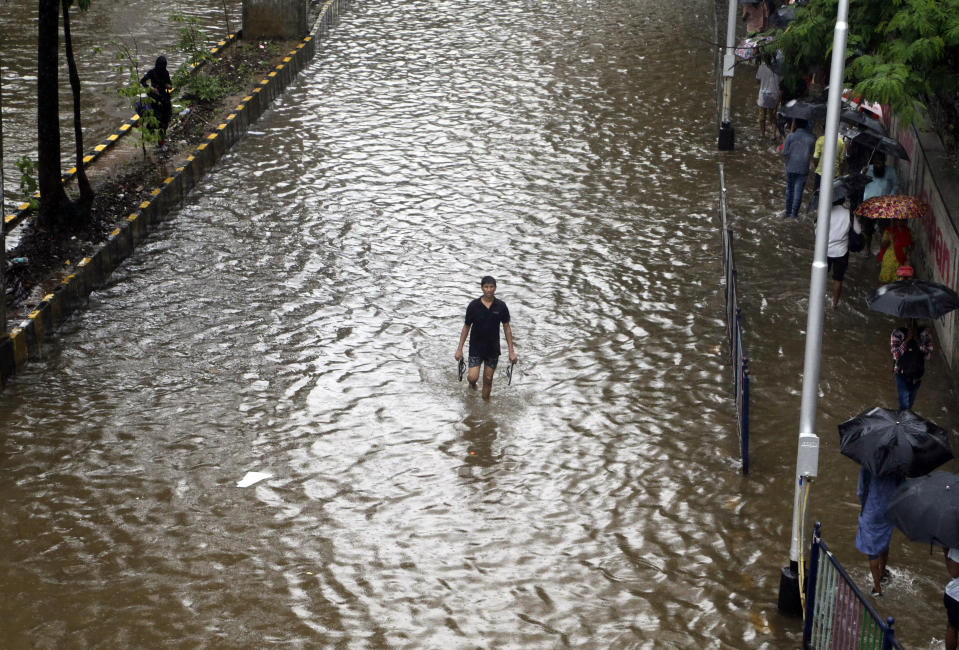 A man wades through a waterlogged street following heavy rains in Mumbai, India, Tuesday, July 2, 2019. Heavy monsoon rains in western India caused at least three walls to collapse onto huts and city shanties, killing more than two dozen people and injuring dozens of others, officials said Tuesday, as forecasters warned of more rains. (AP Photo/Rajanish Kakade)