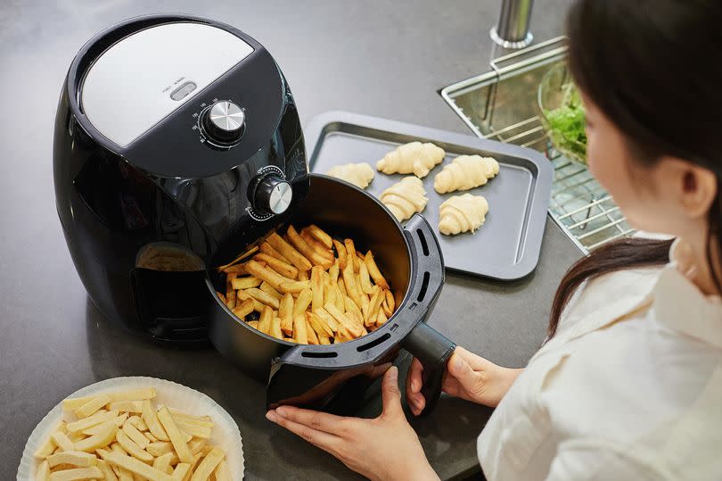 Close-up of person cooking fries in air fryer