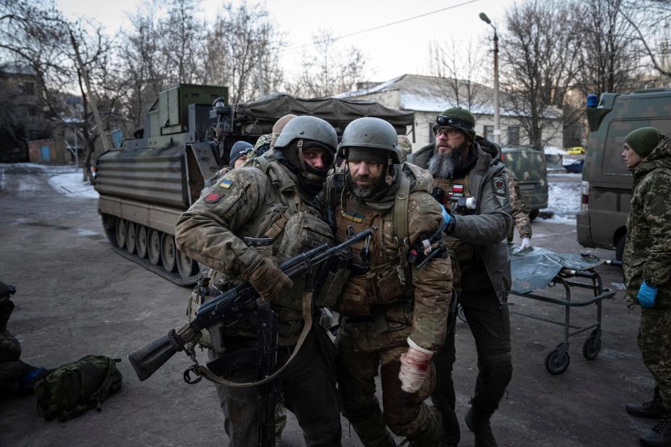 A Ukrainian serviceman carries his injured comrade evacuated from the battlefield into a hospital in Donetsk region, Ukraine, Monday, Jan. 9, 2023.