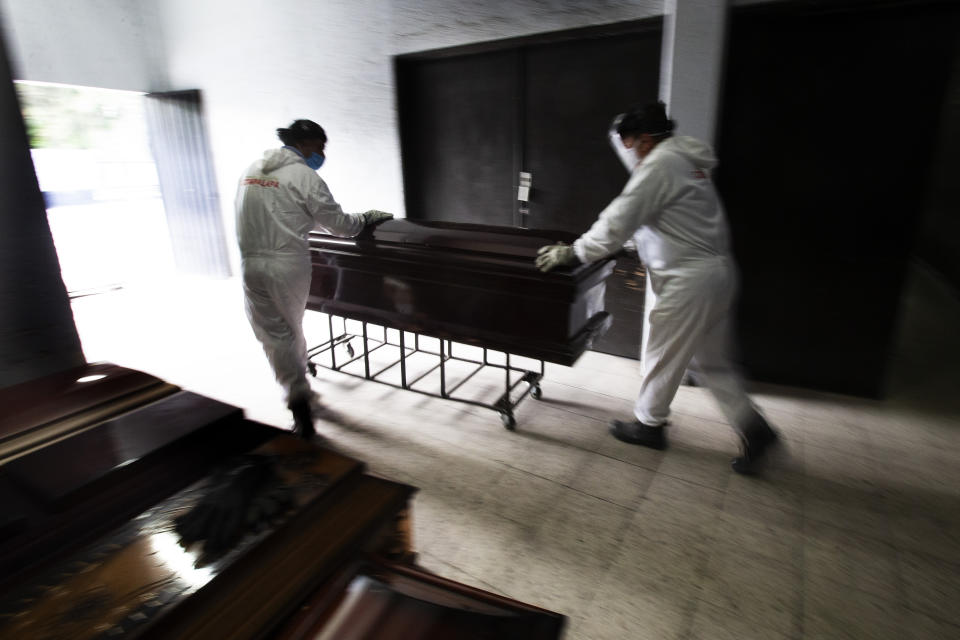 FILE - In this June 4, 2020 file photo, workers in protective gear as a precaution against the coronavirus, remove a coffin that contained the remains of a person who died from the coronavirus, at the crematorium inside the San Nicolas Tolentino cemetery in the Iztapalapa borough of Mexico City. As Mexico approaches 200,000 in officially test-confirmed deaths from COVID-19, the real death toll is probably higher due to the country’s extremely low rate of testing. (AP Photo/Marco Ugarte, File)