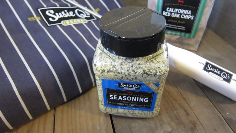 Susie Q's seasoning next to apron and wood chips