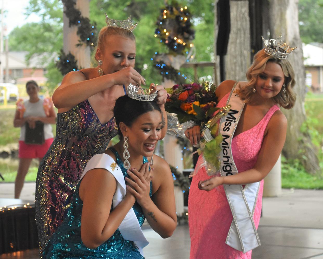 Samantha McGaughy, 21, a senior vocal performance major at Adrian College was crowned Friday, July 14, 2023, as the 2023 Miss River Raisin Festival scholarship program winner during the 28th annual scholarship competition in Blissfield. Crowning McGaughy is 2022 Miss River Raisin Festival Rylee Clairday. Miss Michigan 2023 Maya Schuhknecht, right, looks on.