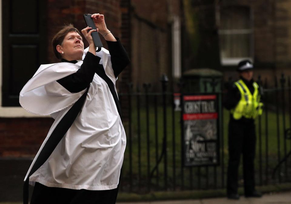A member of the clergy takes photographs outside York Minster before a service to consecrate Reverend Libby Lane as the first female bishop in the Church of England, in York