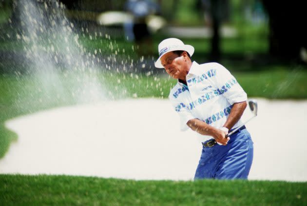 A golfer plays a bunker shot