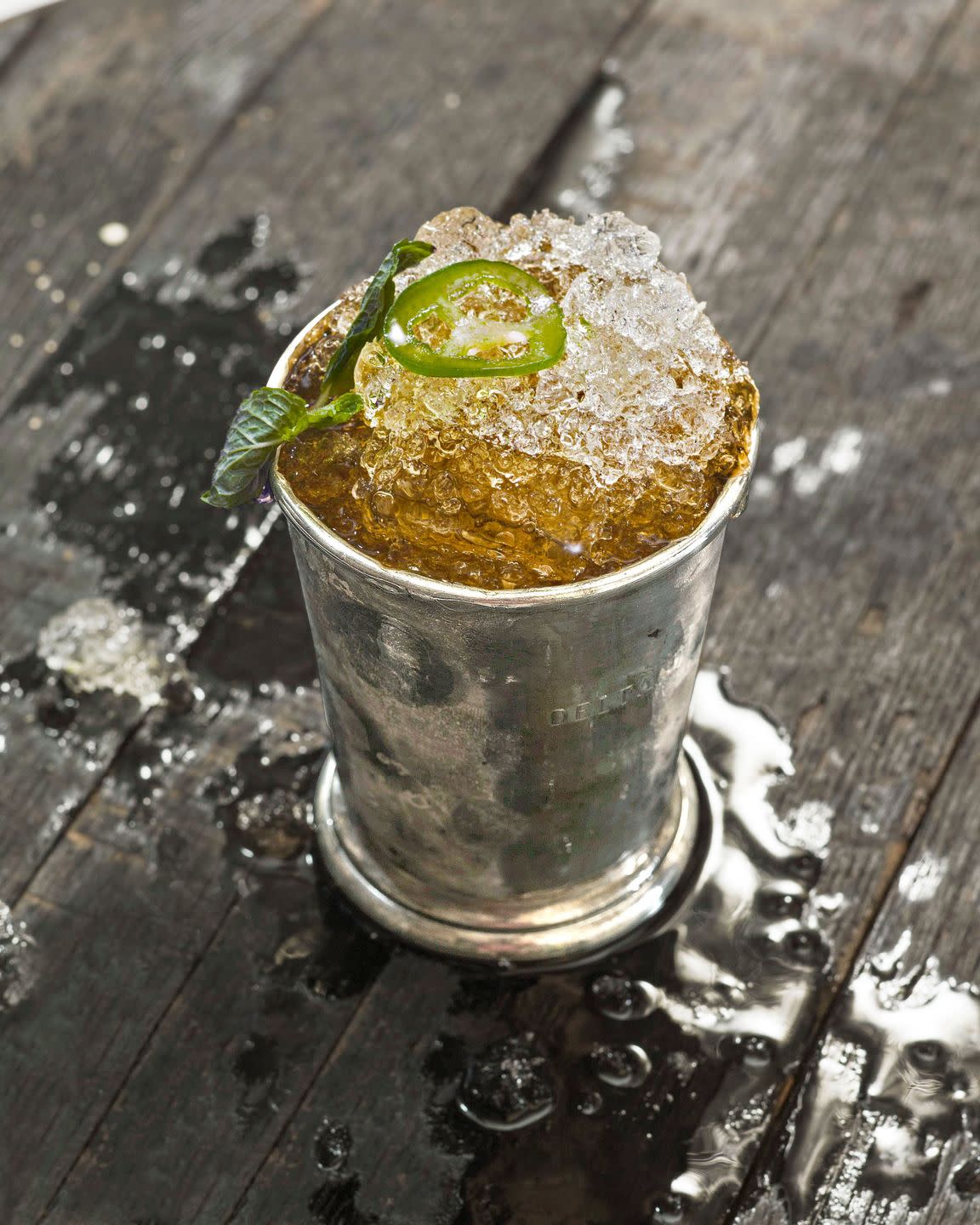 jalapeno spiked bourbon julep in a mint julep cup with fresh mint and sliced jalapeno for garnish