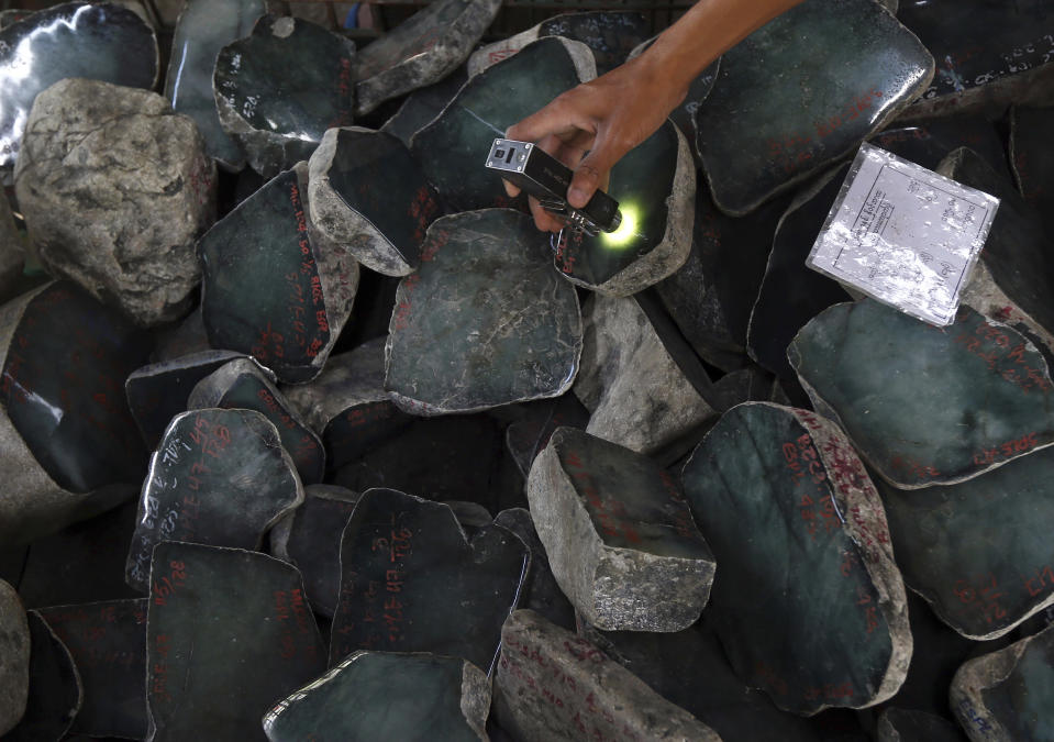 FILE - In this Nov. 13, 2018, file photo, a merchant examines a jade stone displayed at the Gems Emporium in Naypyitaw, Myanmar. In its latest targeted sanctions against Myanmar's military, the U.S. has focused on an army controlled gems business rife with corruption and abuses that is part of one of the junta's most important sources of revenue. (AP Photo/Aung Shine Oo, File)