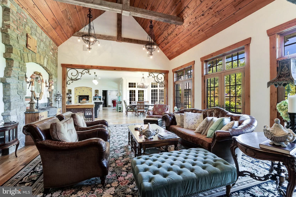 A dated living room with a vaulted ceiling, a studded foot stall, and a leather sofa