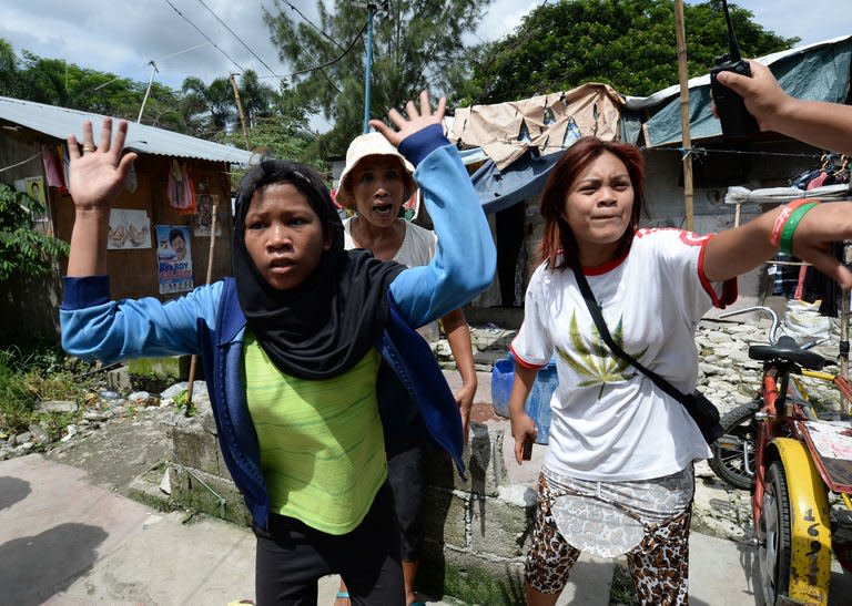 Philippine slum dwellers gesture to anti-riot policemen (not pictured) during a clash in Manila, on July 1, 2013. Slum dwellers hurling rocks, improvised explosives and human excrement fought running battles with riot police around a sprawling Manila shanty town that is set for redevelopment