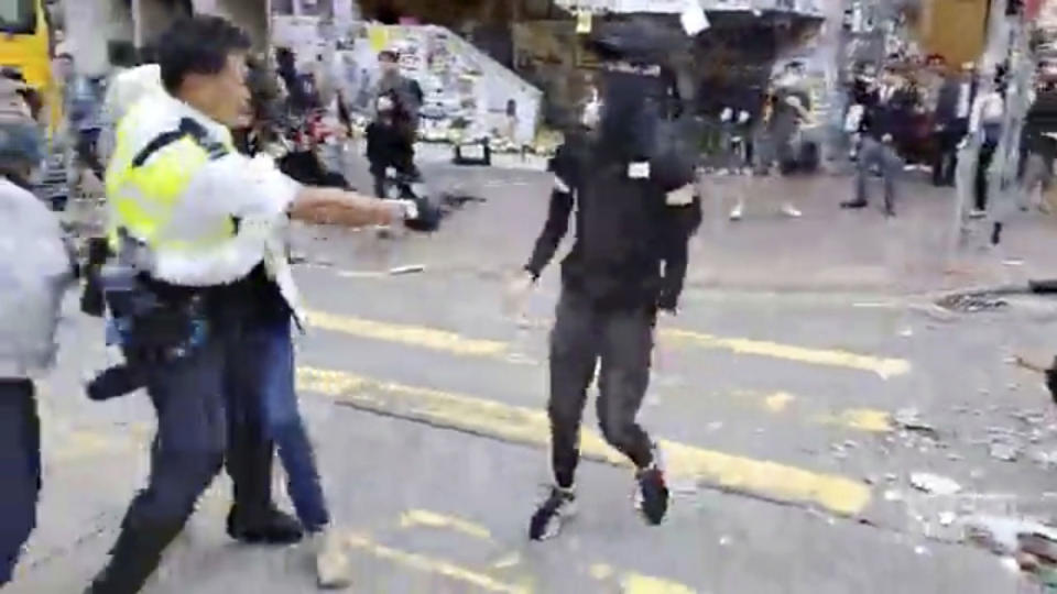 In this image made from video, a police officer, left, prepares to shoot a protester, center, in Hong Kong Monday, Nov. 11, 2019. The police shot the protester as demonstrators blocked subway lines and roads during the Monday morning commute. (Cupid Producer via AP)