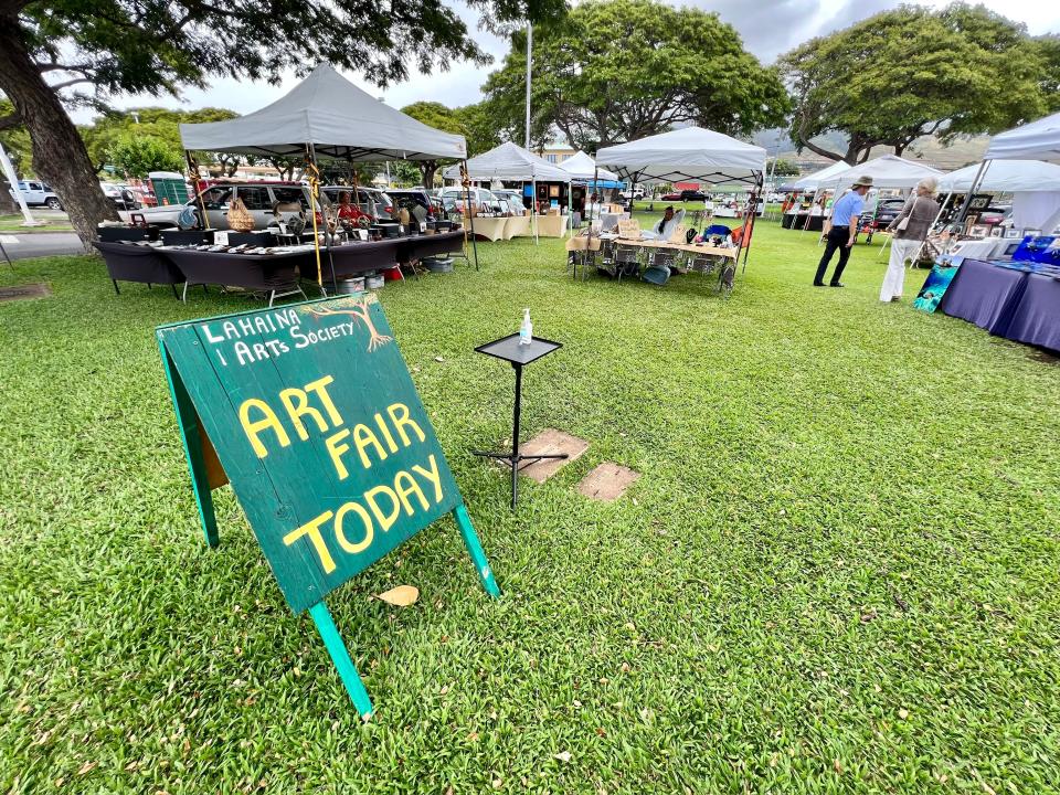 sign for art fair in hawaii with tents in the background