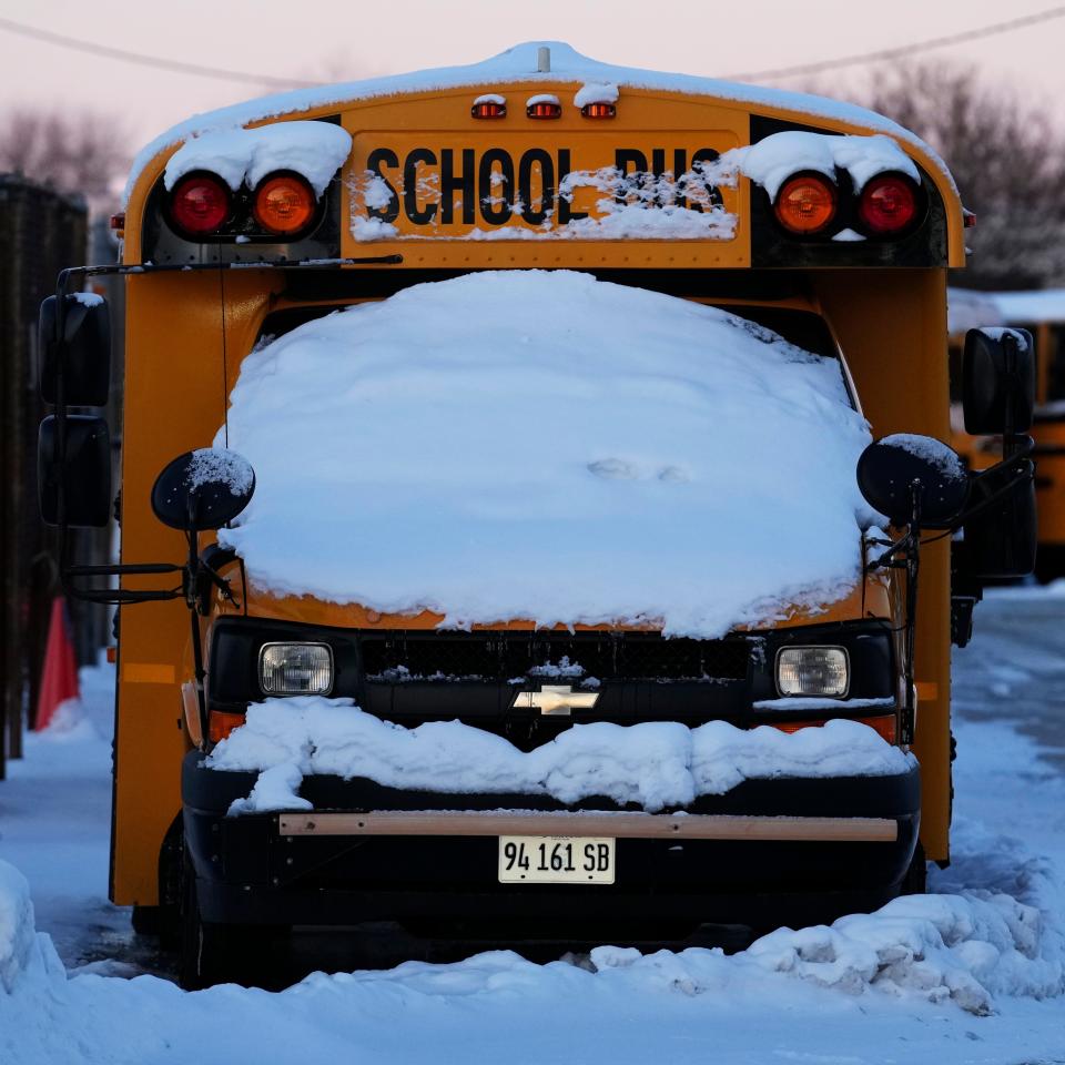 A snow covered school bus sits in a parking lot in Wheeling, Ill., Tuesday, Jan. 16, 2024. Illinois school cancels classes Tuesday due to extreme cold.