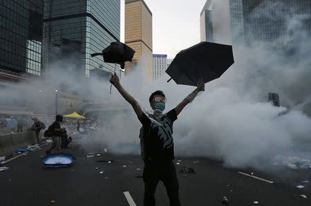 A protester (C) raises his umbrellas in front of tear gas which was fired by riot police to disperse protesters blocking the main street to the financial Central district outside the government headquarters in Hong Kong, in this September 28, 2014 file photo. REUTERS/Tyrone Siu/Files