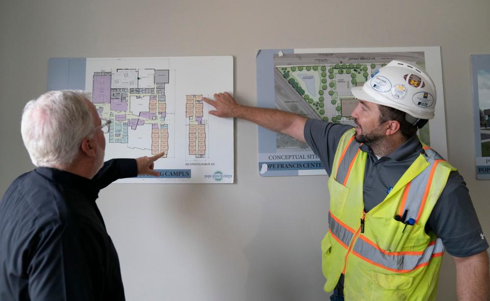 Father Tim McCabe, SJ, president and CEO of the Pope Francis Center in Detroit, left, looks at floor plans with the J.S. Vig Construction project manager before a tour Thursday, Sept. 7, 2023, of the new Pope Francis Center-Bridge Housing Campus,  located in the Core City area of Detroit, that will expand his team's ability to help house and treat the homeless population in the 60,000-square-foot facility by offering housing, meals, health care, including mental health, an athletic facility, computer lab and warming shelter for homeless people during potential extreme weather events.
