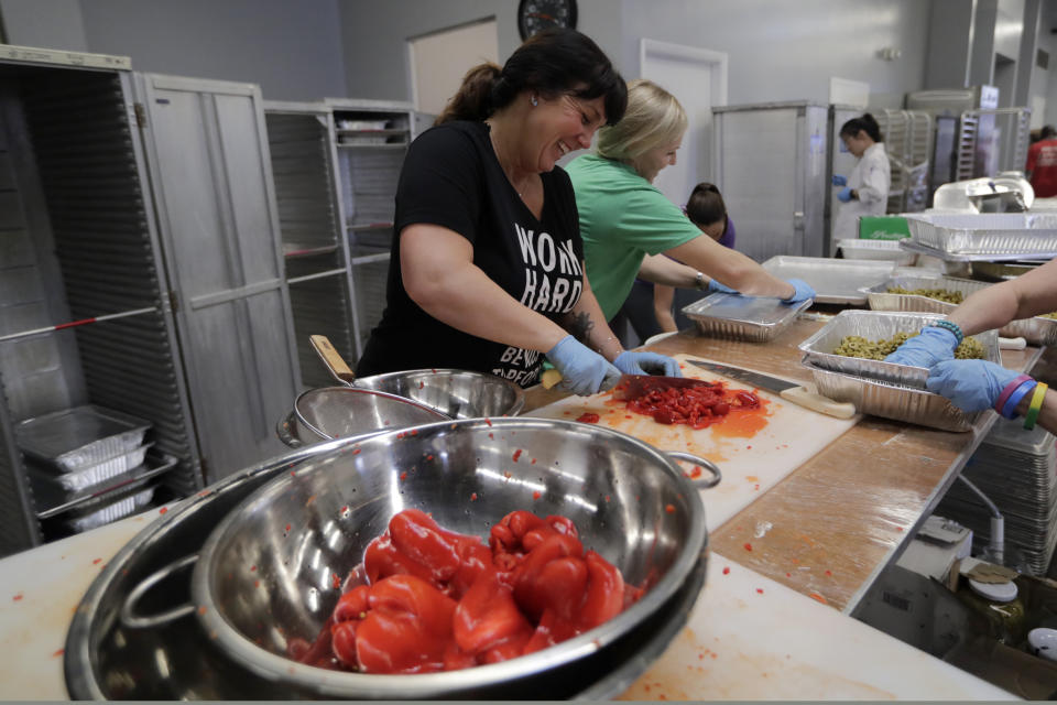 In this Thursday, Feb. 20, 2020 photo, Jessica Weston, of the Weston Kewpees, prepares food for the burger bash competition at the Miami Rescue Mission in Miami. From Rachael Ray to Bobby Flay, the biggest names in the culinary world are in Miami starting Thursday for the South Beach Wine and Food Festival. And they're getting help in their prep kitchen from an unlikely source, a local homeless shelter. The festival partnered with the Miami Rescue Mission and Florida International University's culinary school. (AP Photo/Lynne Sladky)